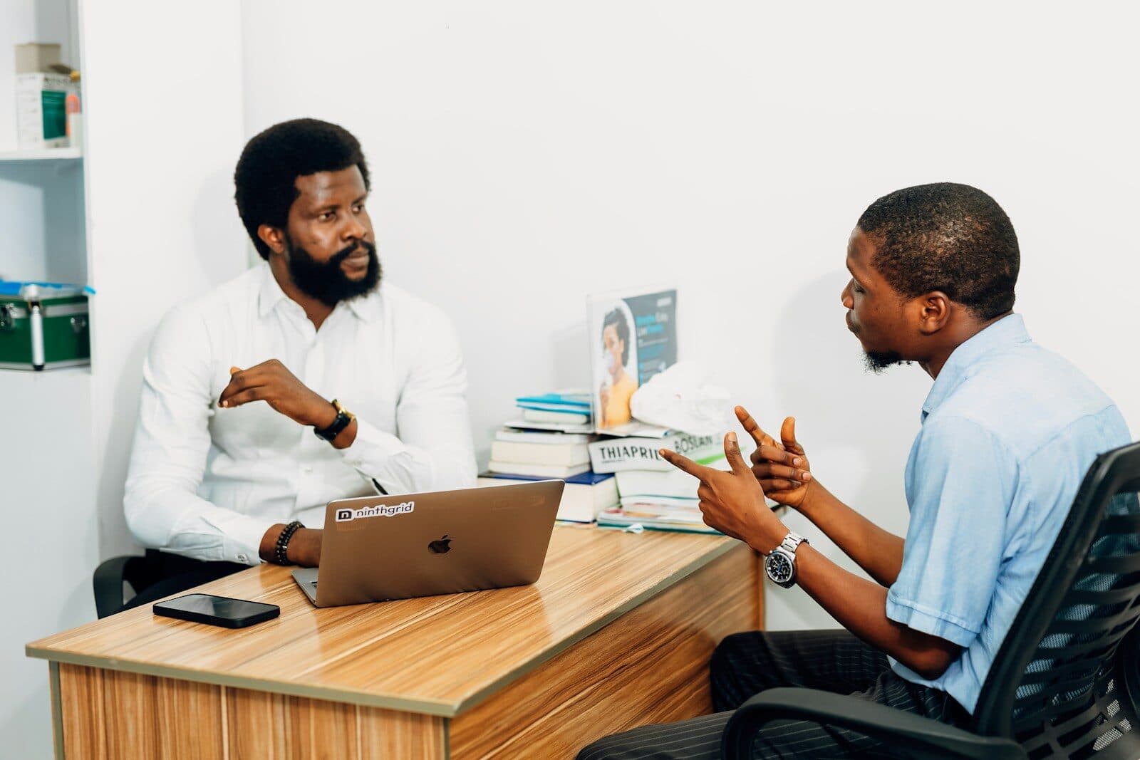 Two men sitting at a desk talking to each other
