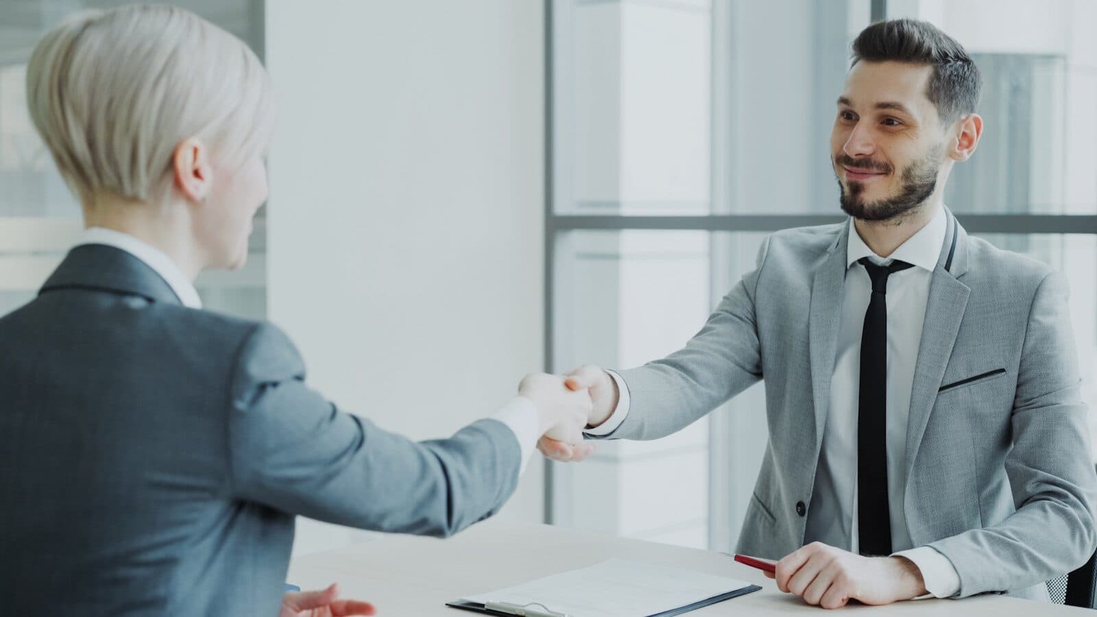 Two professionals shaking hands across a table.